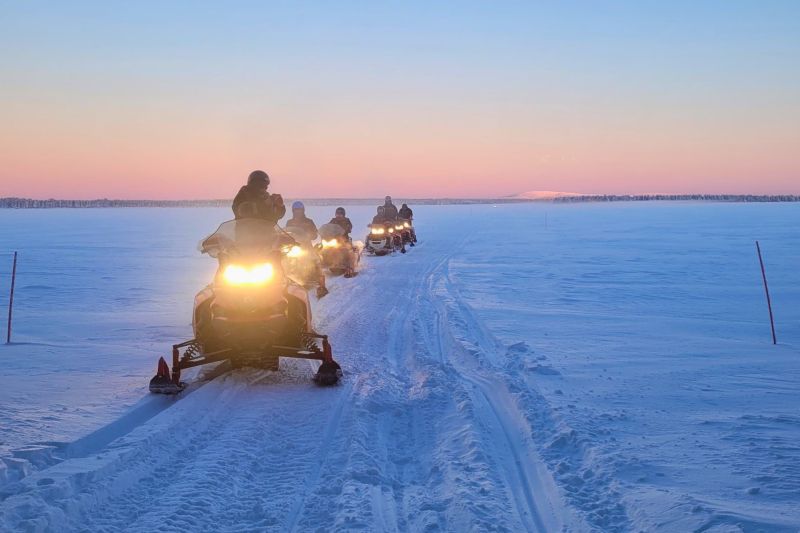 Moottorikelkkasafari Rukan talvisissa maisemissa. Opas johdattaa safariryhmää talvella järven jäällä.